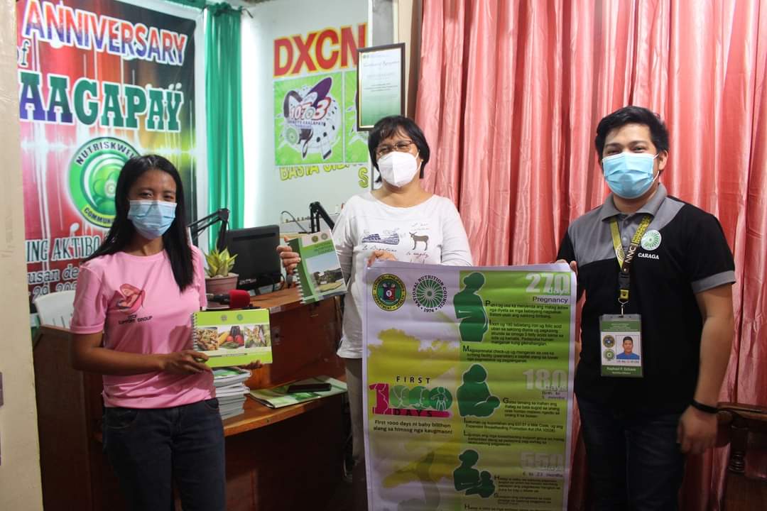 Radyo Kaagapay Station Manager Elizabeth Badajos receiving the IEC materials from NNC Caraga.